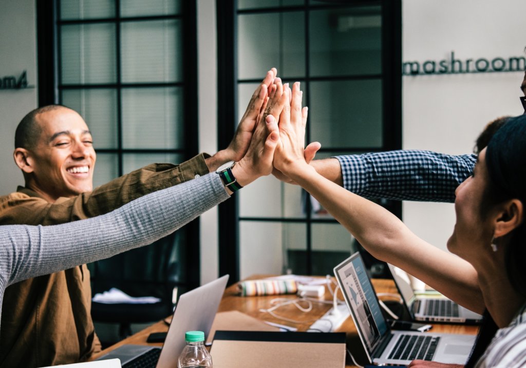 employees high fiving at a desk