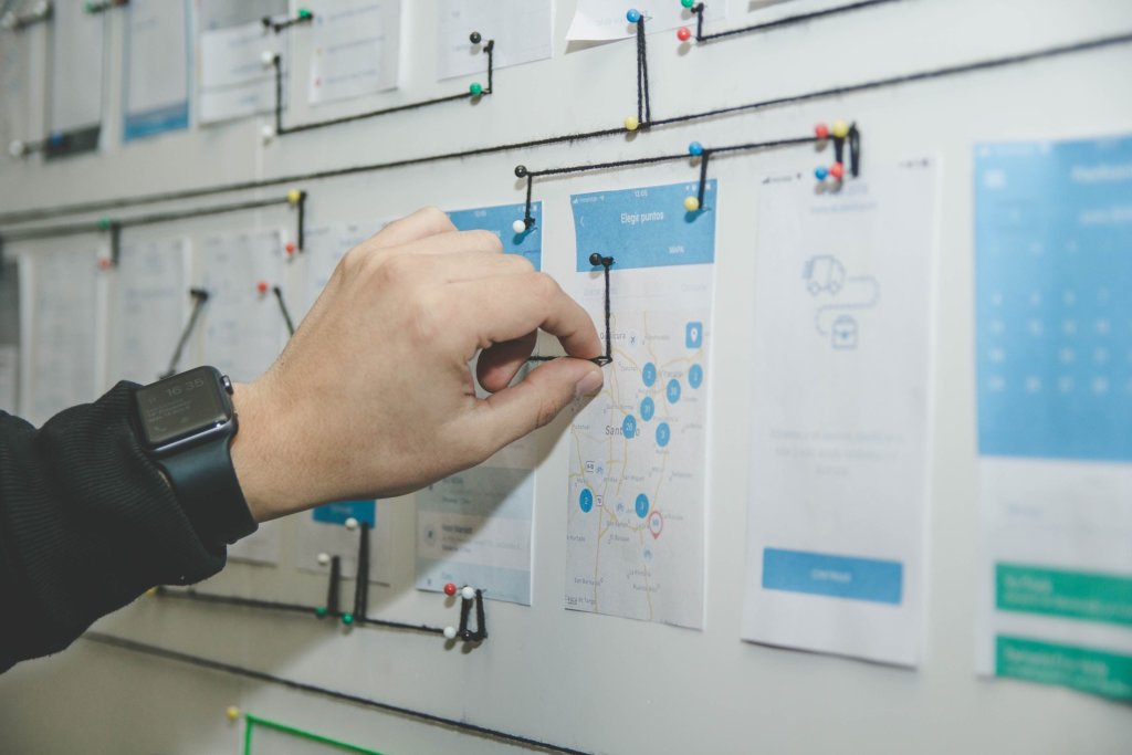 person putting thumbtacks into a piece of paper on a board