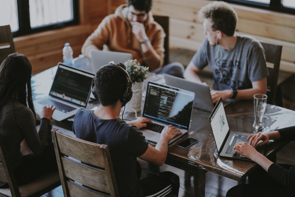 Team sitting around a table with laptops out. When should you scale the product team?